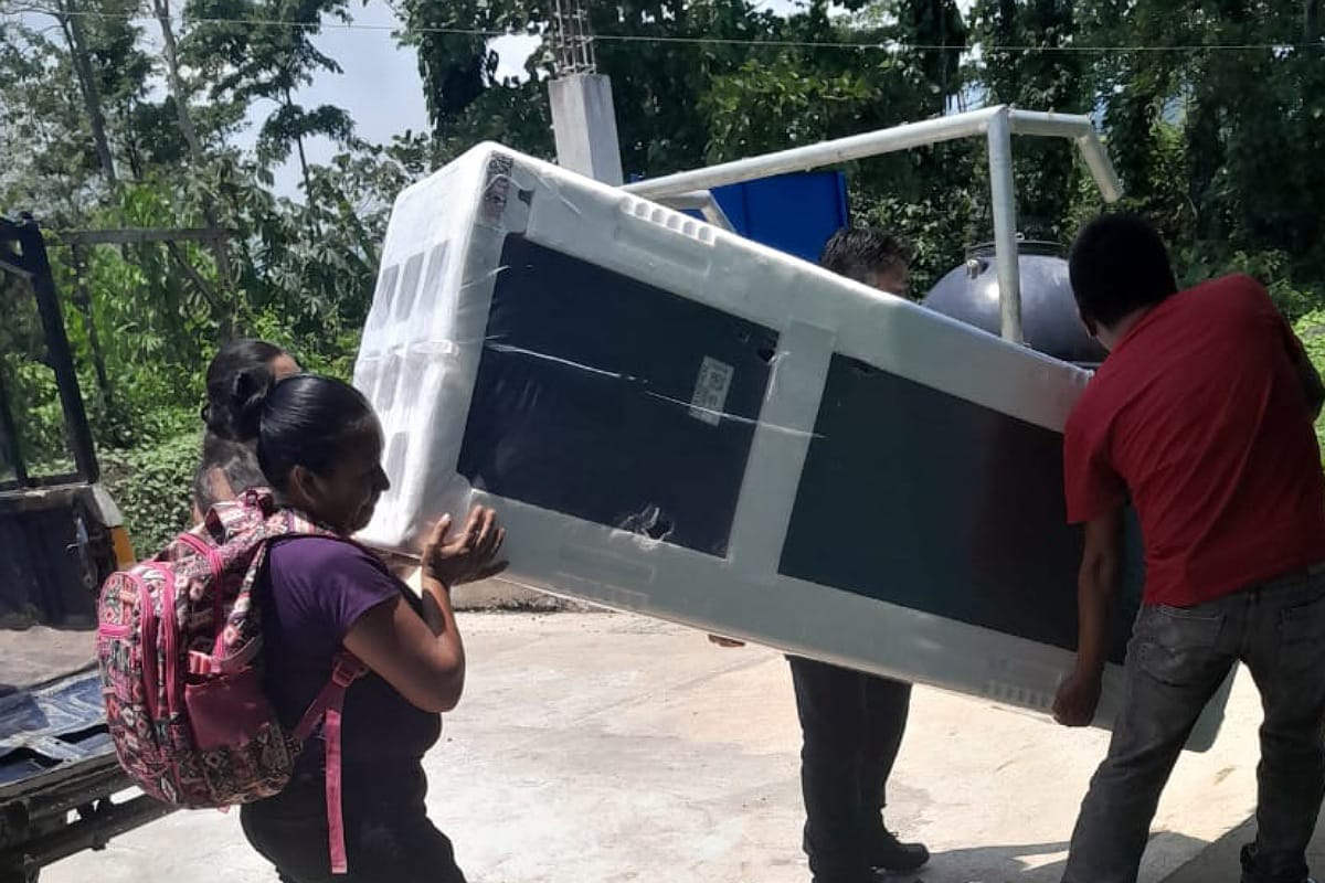 Locals carry the new refrigerator inside of the school
