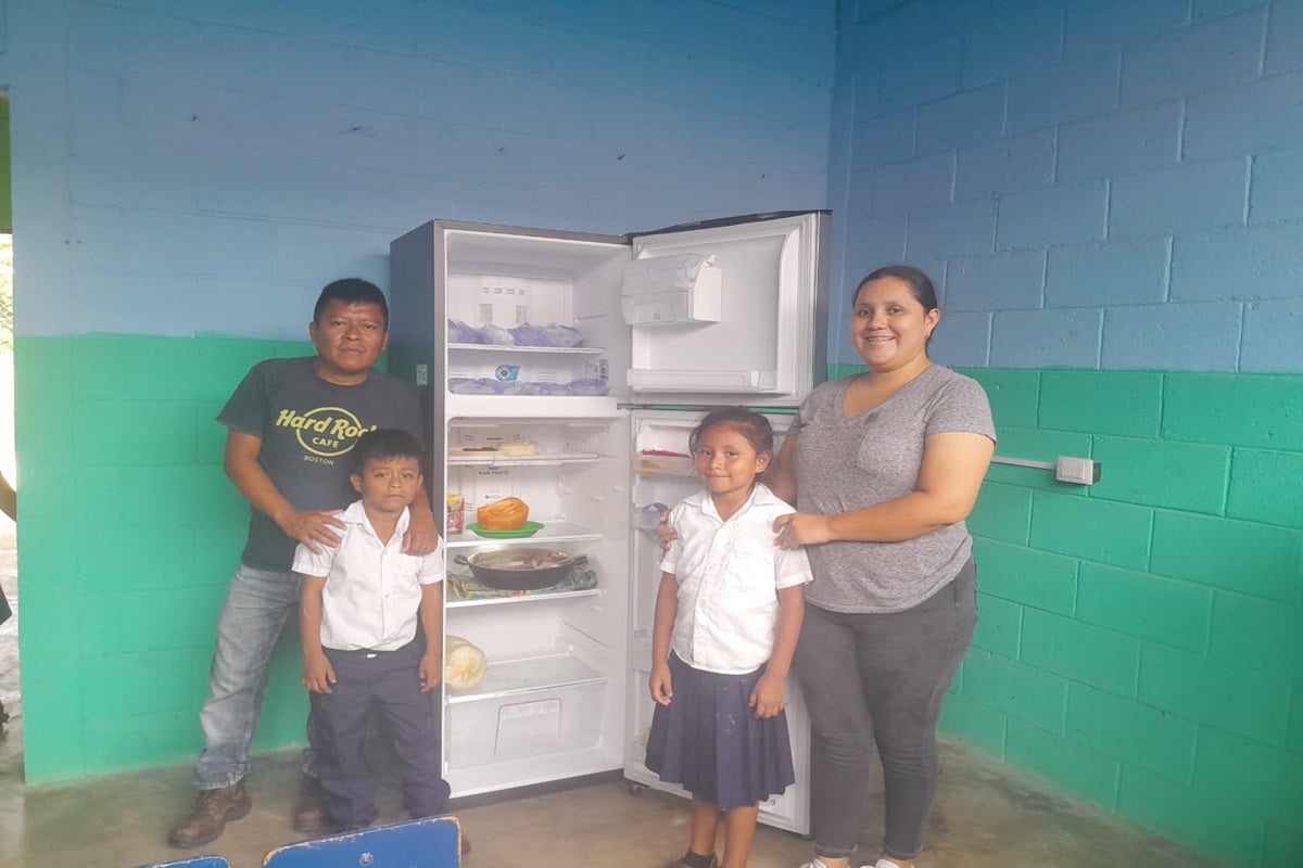 Locals pose in front of the donated refrigerator 
