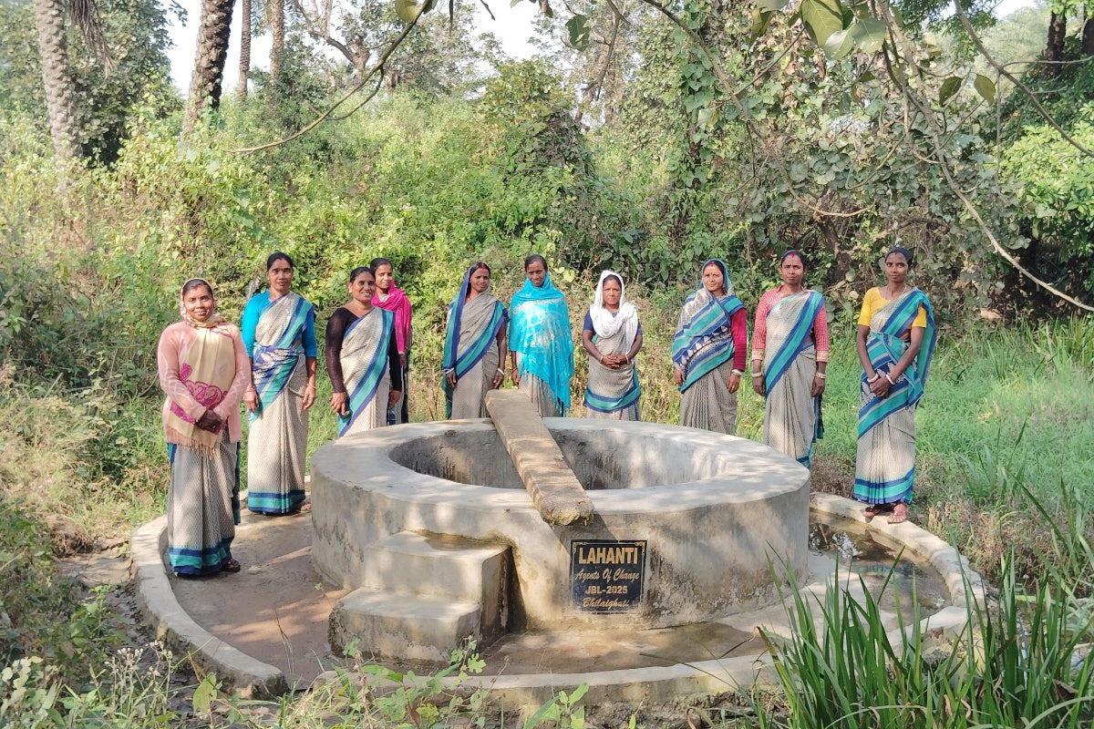 A completed water well in India surrounded by locals 